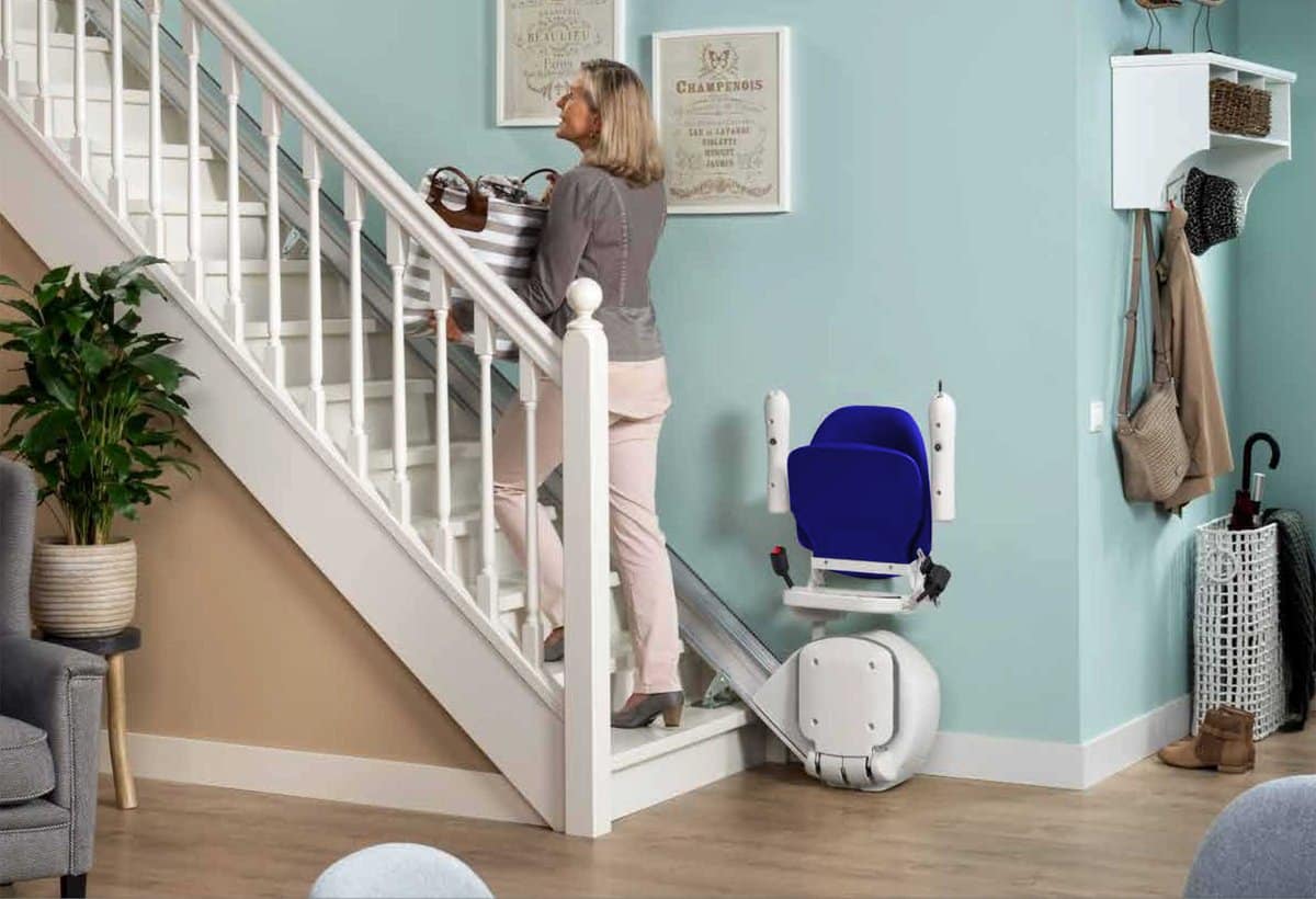 Persona mayor usando silla salvaescaleras en su vivienda
